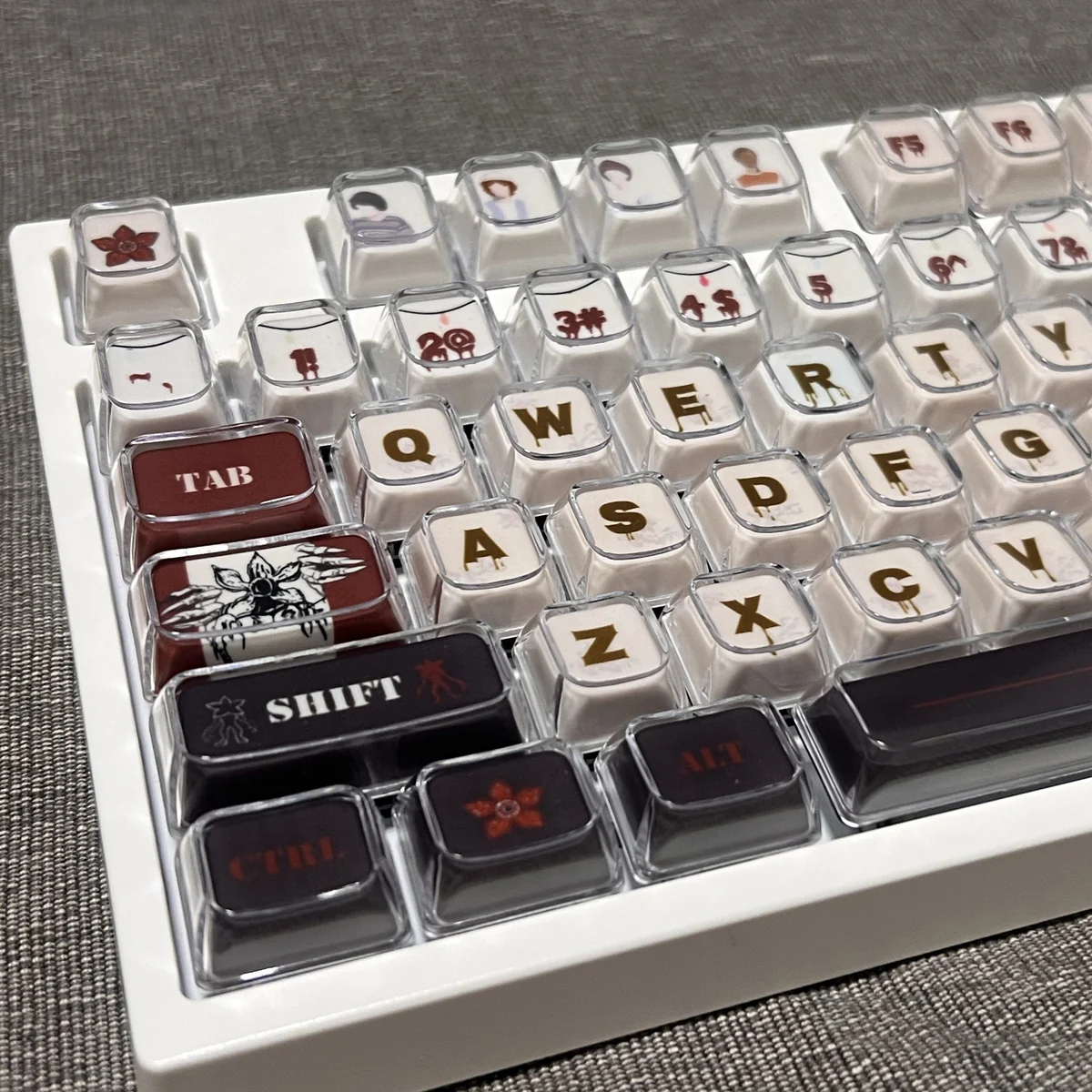A gallery view of Stranger Things Amber Pudding PBT keycaps, revealing their iconic translucent amber glow and playful retro 80s Hawkins aesthetic.