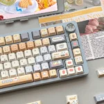 An angled view of the PBT Sushi Keycap Set, featuring vibrant Japanese Sushi House abstract designs and elegant 'Folded Shadow' geometric patterns.