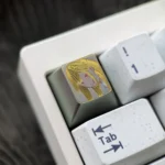 Hand-carved titanium anime keycap featuring Marin Kitagawa portrait with golden linework, mounted on a white mechanical keyboard.
