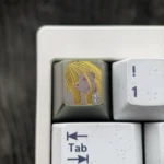 Hand-carved titanium anime keycap showcasing Marin Kitagawa with a blonde portrait and golden linework on a muted titanium surface.