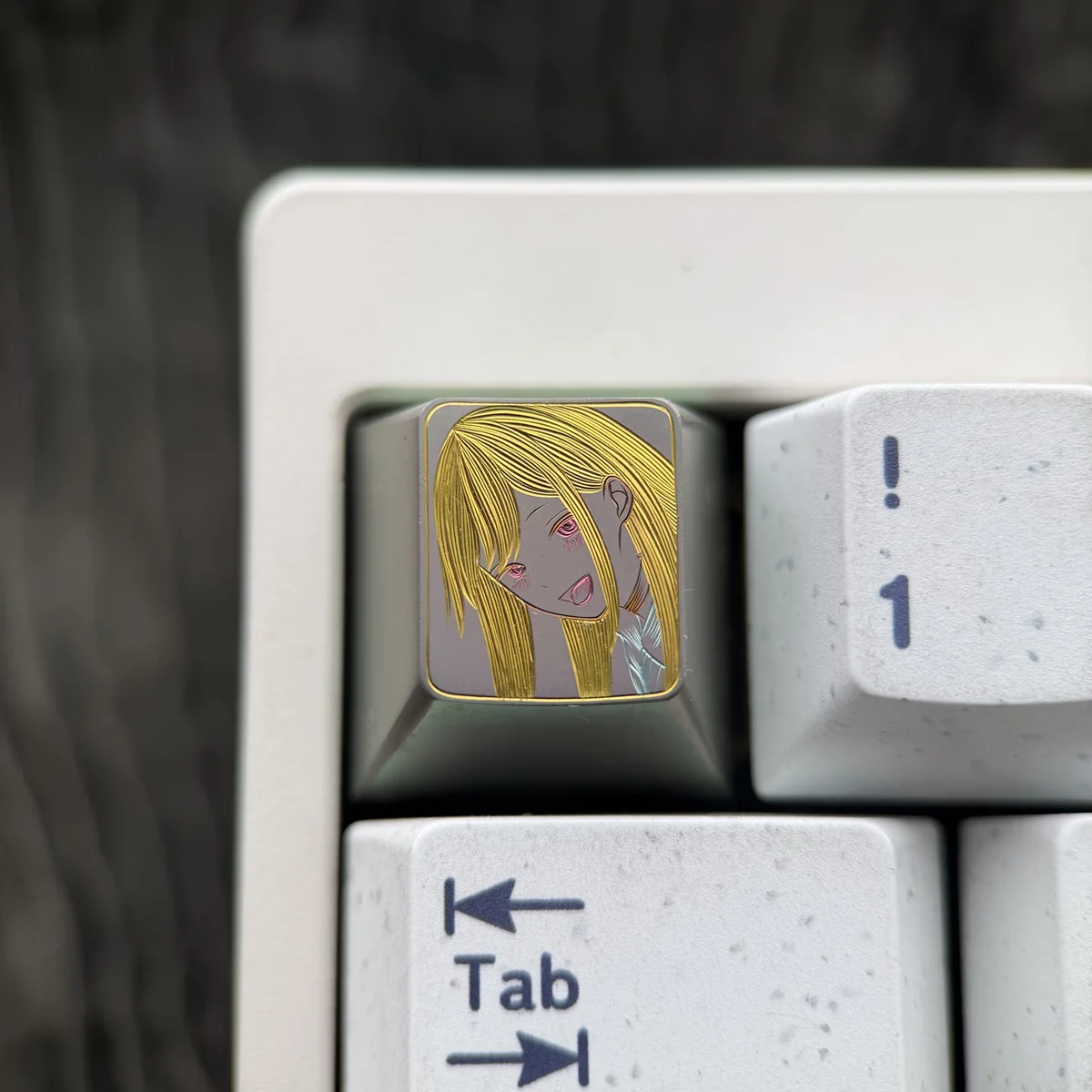 Hand-carved titanium anime keycap showcasing Marin Kitagawa with a blonde portrait and golden linework on a muted titanium surface.