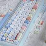 Close-up of a Cozy Winter Bear PBT Dye-sub Keycap set, highlighting playful bear designs and snowy forest details in soft, muted tones.