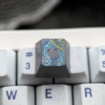 Close-up view of the hand-carved Wuthering Waves The Shorekeeper titanium ESC keycap, showcasing its intricate details and vibrant metallic finish from a unique angle.